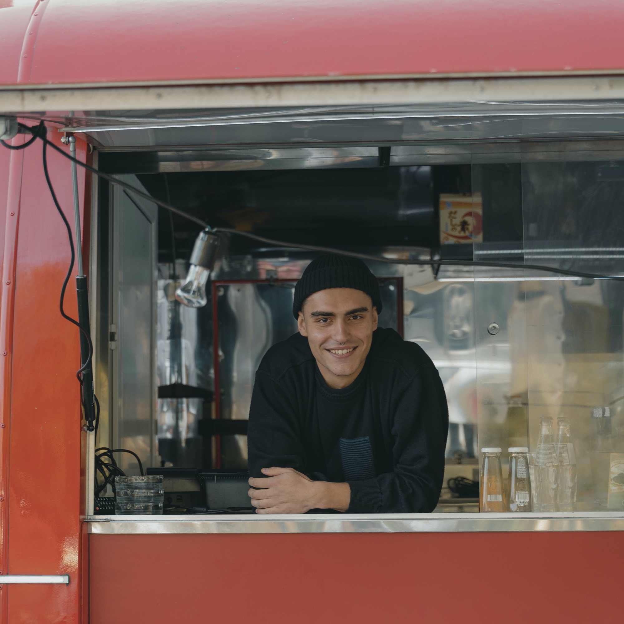 a smiling man leans out of the window of a food truck